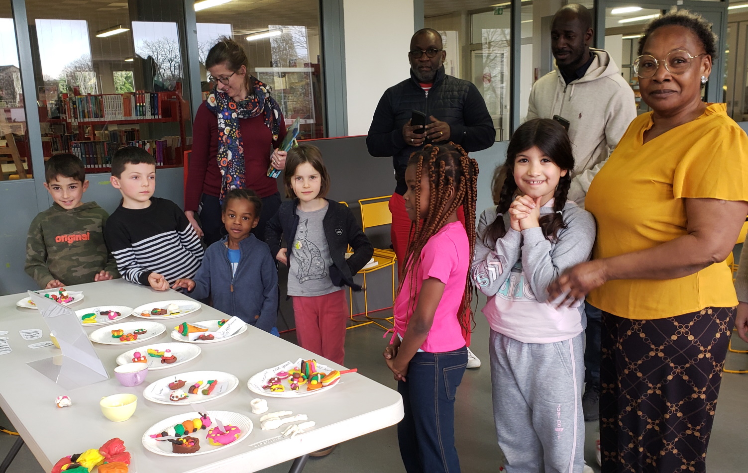 Enfants et adultes devant un buffet de mignardises en pâte à modeler