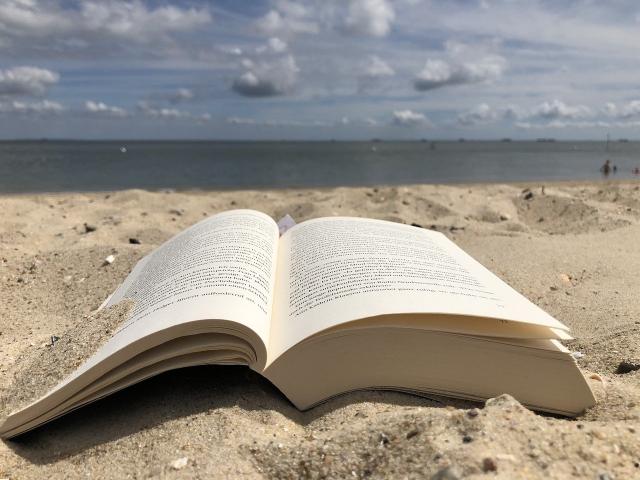 un livre ouvert sur une plage de sable, avec la mer et le ciel à l'horizon